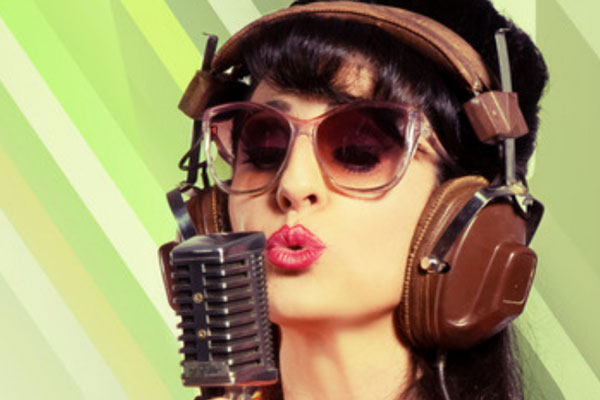 A photo of a singer in a retro hairdo, red lipstick, graduated sunglasses, wearing a vintage brown leather clad headphone, singing in to a retro microphone.